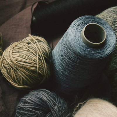 a top down view of dark colour balls of yarn and sewing spools
